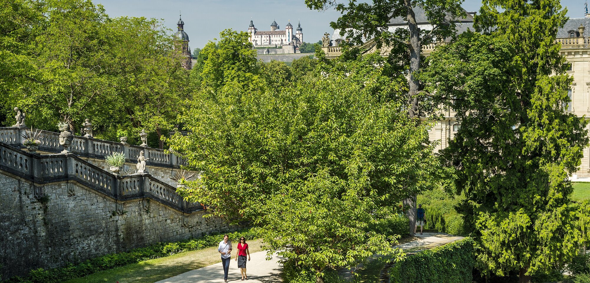 Grüne Parkanlage mit Bäumen und Blick auf eine Festung im Hintergrund