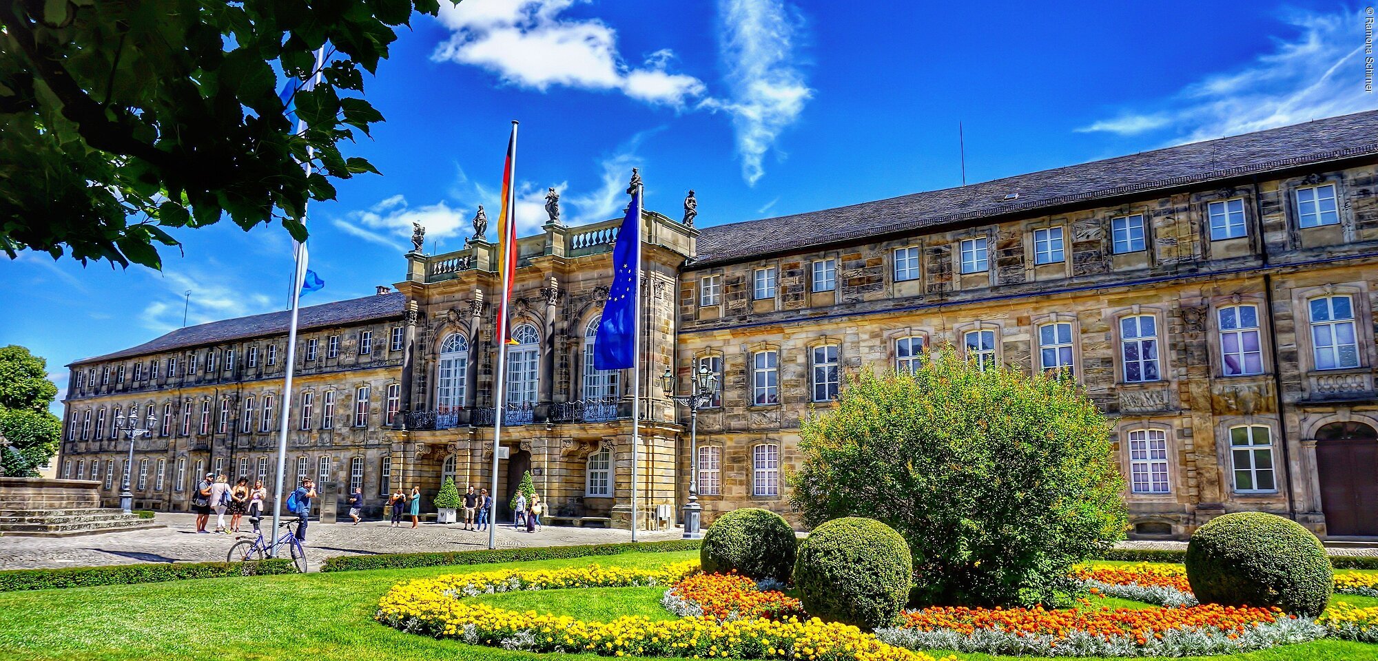 Ein prachtvolles Schloss, davor eine grüne Gartenanlage.