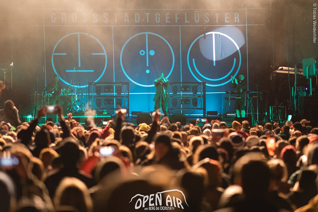Open-Air-Konzert mit Band auf Bühne und Publikum bei Nacht