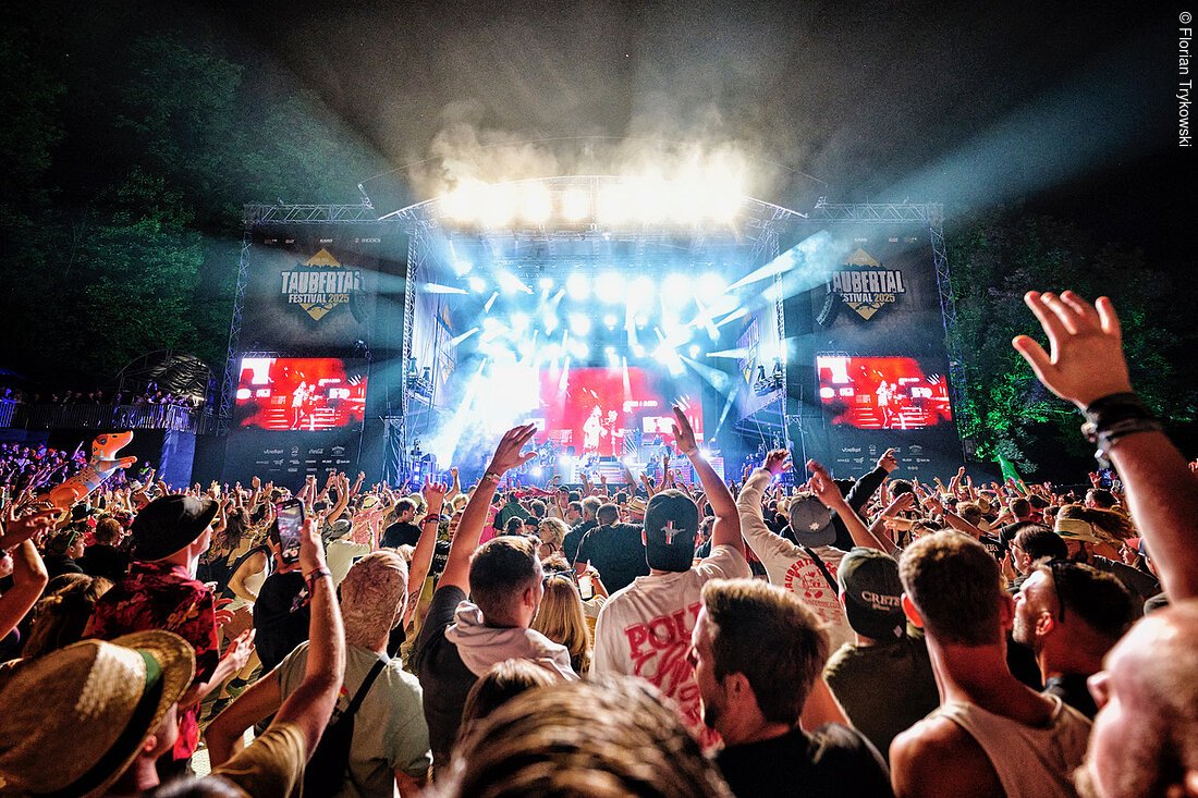 Menschenmenge vor beleuchteter Bühne beim Taubertal Festival 2023 in der Nacht.
