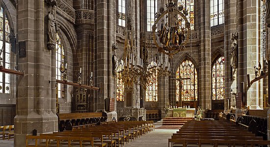 Innenraum einer gotischen Kirche mit hohen gewölbten Decken, Säulen und Kirchenbänken, Altar im Hintergrund